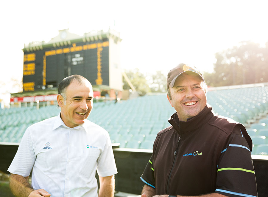 groudskeeper and old man standing on the Adelaide Oval in front of a scoreboard